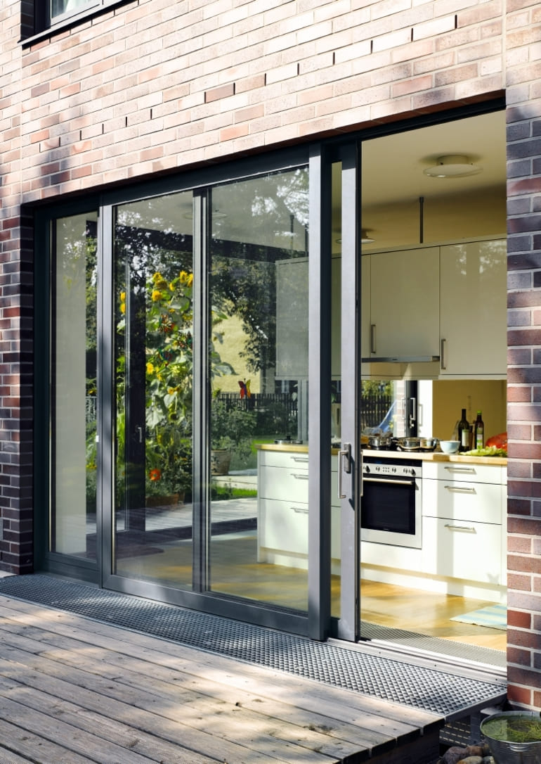 Schiebetür aus Aluminium zwischen Küche und Terrasse bei Tageslicht Schiebetür aus Aluminium zwischen Küche und Terrasse bei Tageslicht